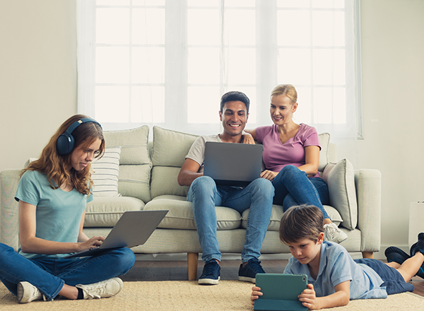 family on their computers, laptops, tablets in living room on couch and floor